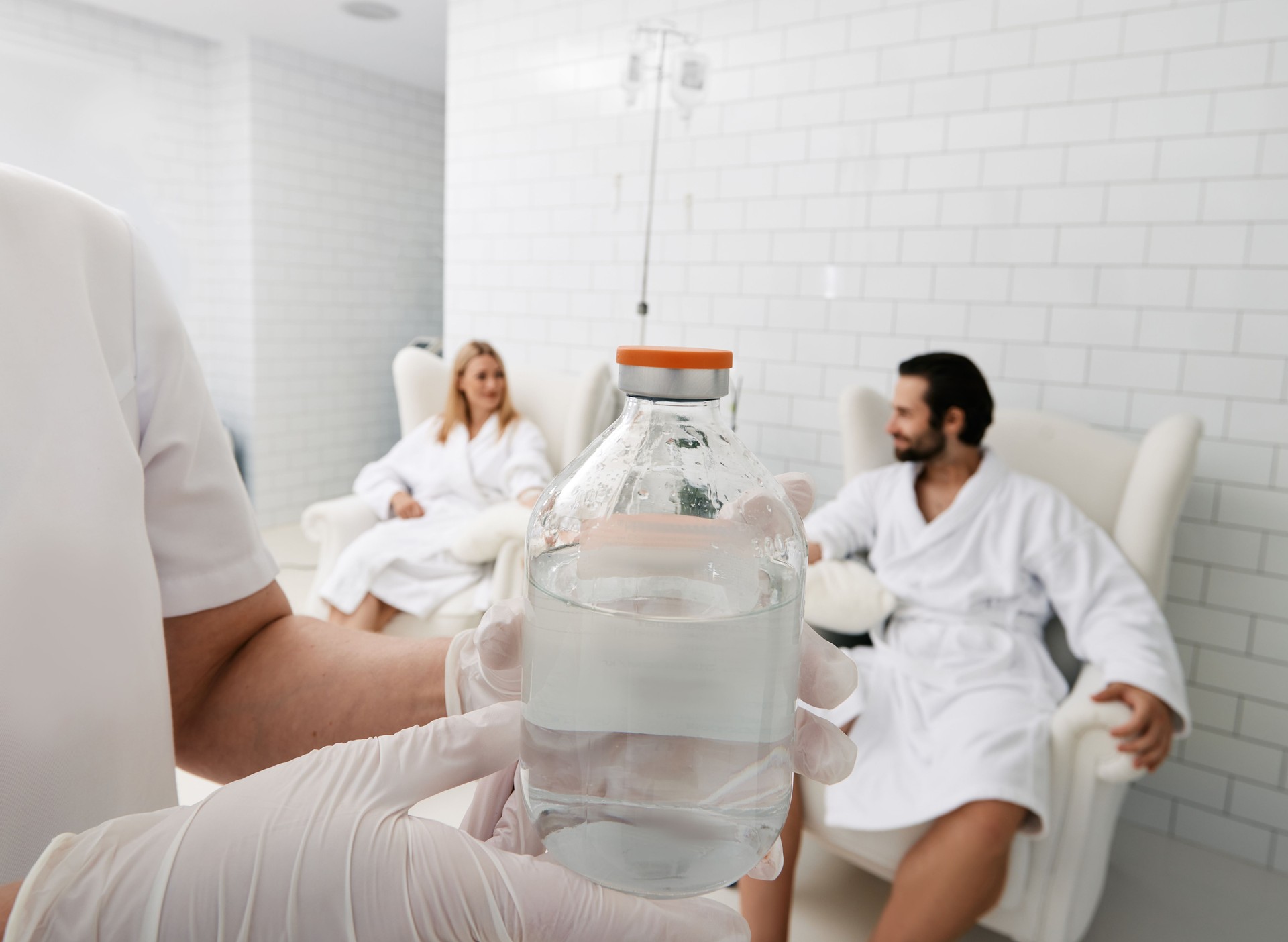 Jar with vitamin cocktail for intravenous therapy in hands of healthcare worker for wellness center patients. Maintenance of human immune system with vitamin IV infusion therapy